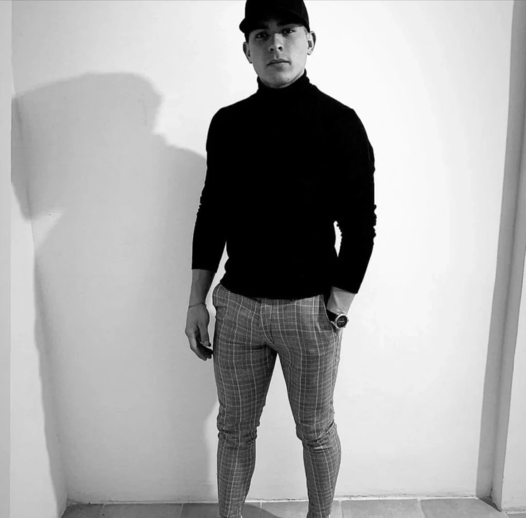 Jesus, a master barber at PercyCutz Barber Shop Windsor posing in a black turtleneck and plaid trousers.